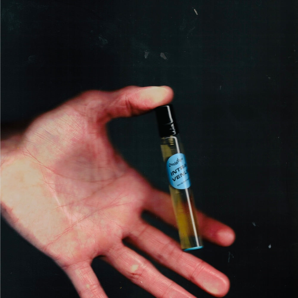 Hand holding a 7.5 mL travel spray of Chronotope Perfume’s Intra Venus Eau de Parfum, an avant-garde white-floral scent with mastic and mercaptan, widely regarded as the most photorealistic hyacinth perfume ever created.