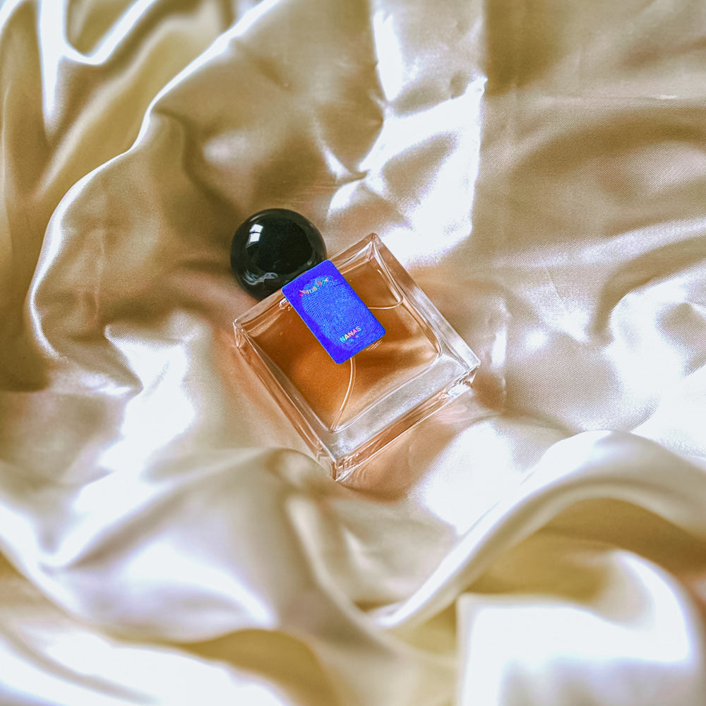 A 30mL bottle of Nanas Eau de Parfum by Chronotope Perfume, nestled in glistening cream, shiny fabric.