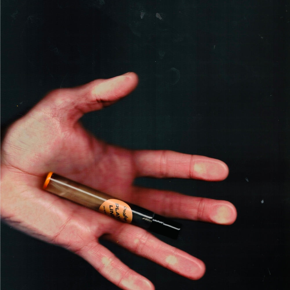 Hand holding a 7.5 mL travel spray of Chronotope Perfume’s Playalinda Eau de Parfum, an avant-garde unisex fruity-floral perfume featuring notes of juicy peach, basil, seaweed, and suntanned skin.