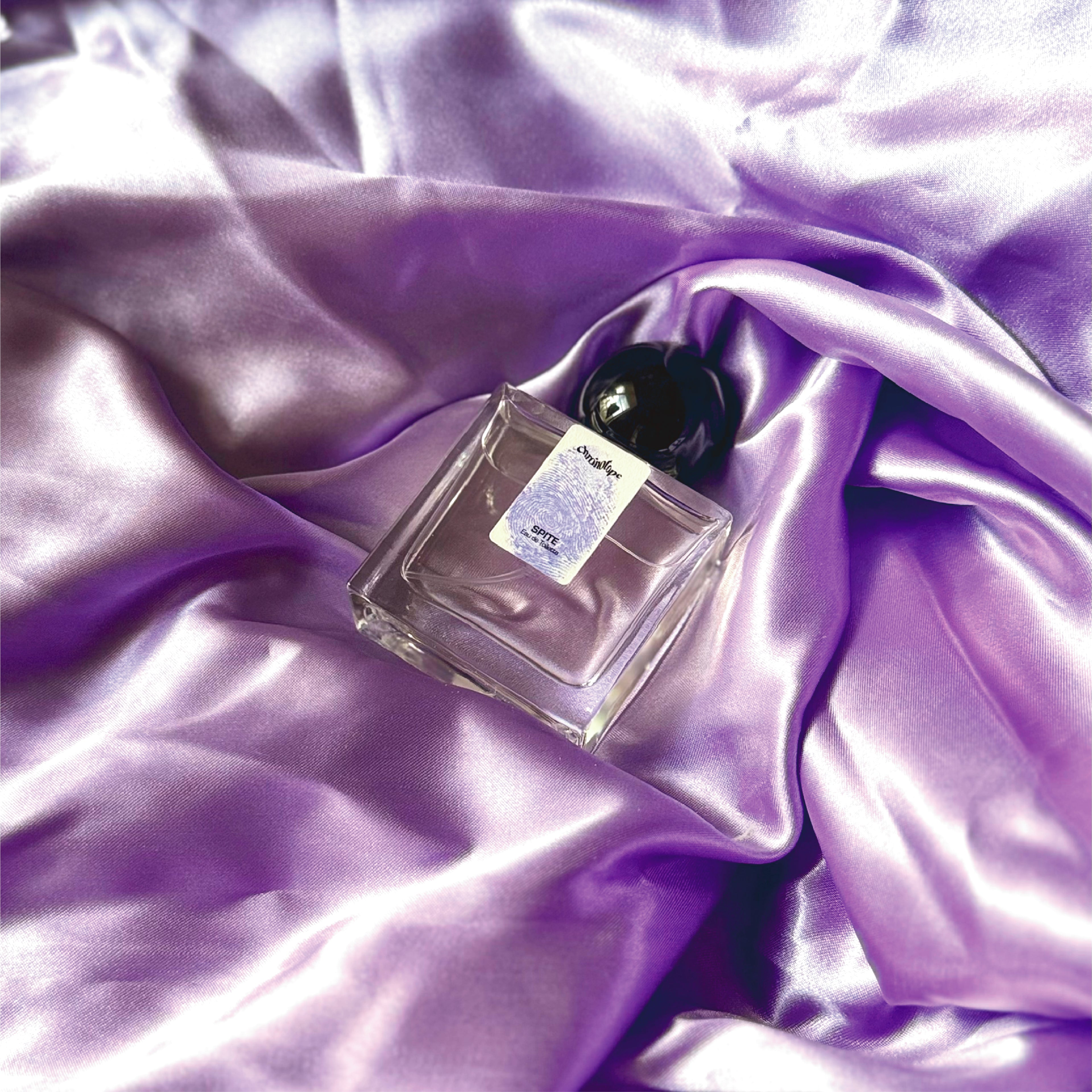 Chronotope perfume’s Spite EdT lies in a shimmering nest of fabric in the same mauve color as the thumbprint on the perfume bottle’s label.