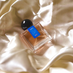 A 30mL bottle of Nanas Eau de Parfum by Chronotope Perfume, nestled in cream, shiny fabric.