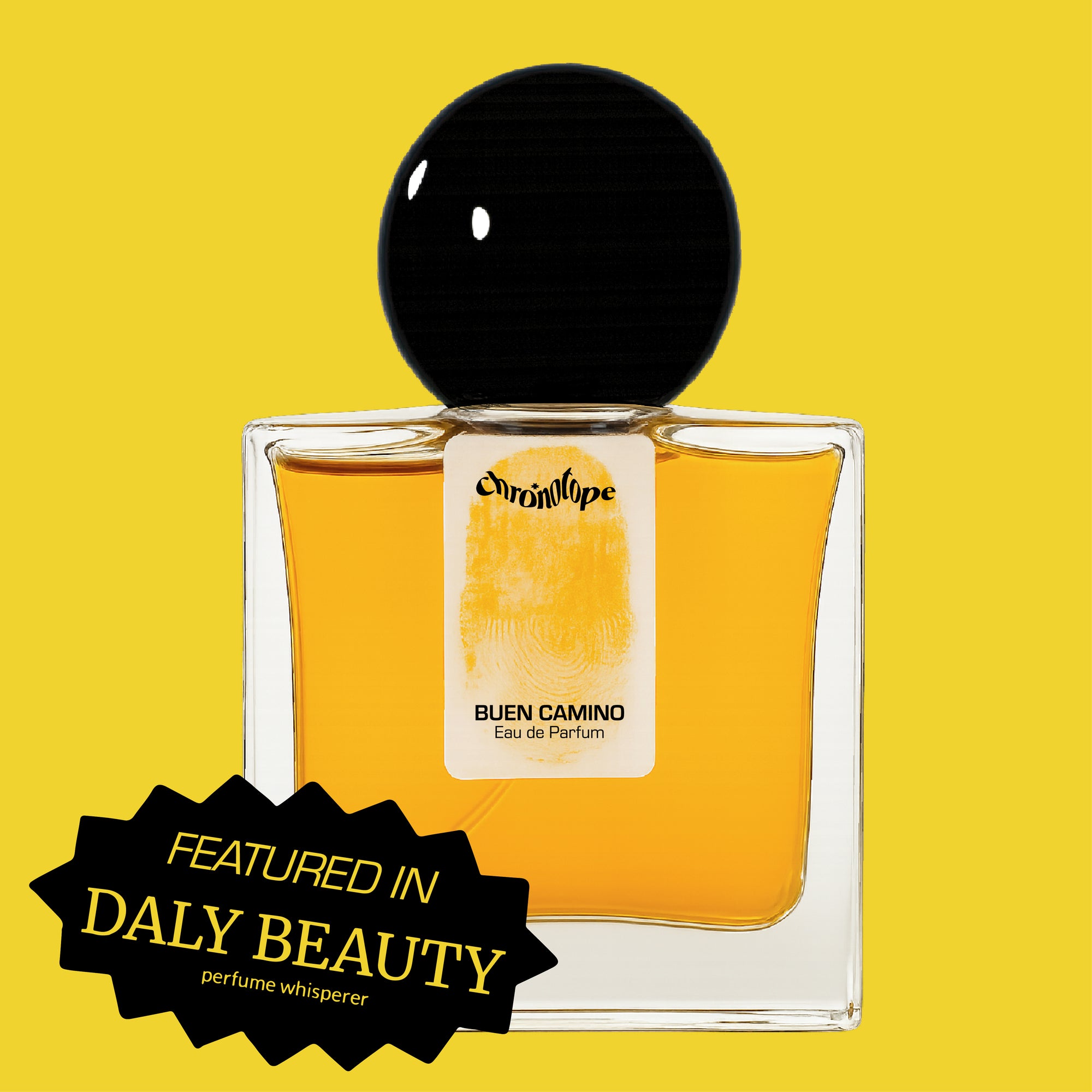 Digital rendering of Chronotope Perfume’s Buen Camino Eau de Parfum bottle with a white label stamped with the perfumer’s thumbprint in Pilgrim Yellow, containing dark toffee-colored perfume, and set against a matching Pilgrim Yellow background with a badge noting press coverage in Daly Beauty.
