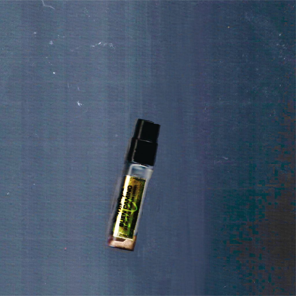2mL spray sample of Chronotope Perfume’s Buen Camino Extrait de Parfum, featuring a golden enameled tip and matching Amberlit Gold label, shown against a dark gray background.