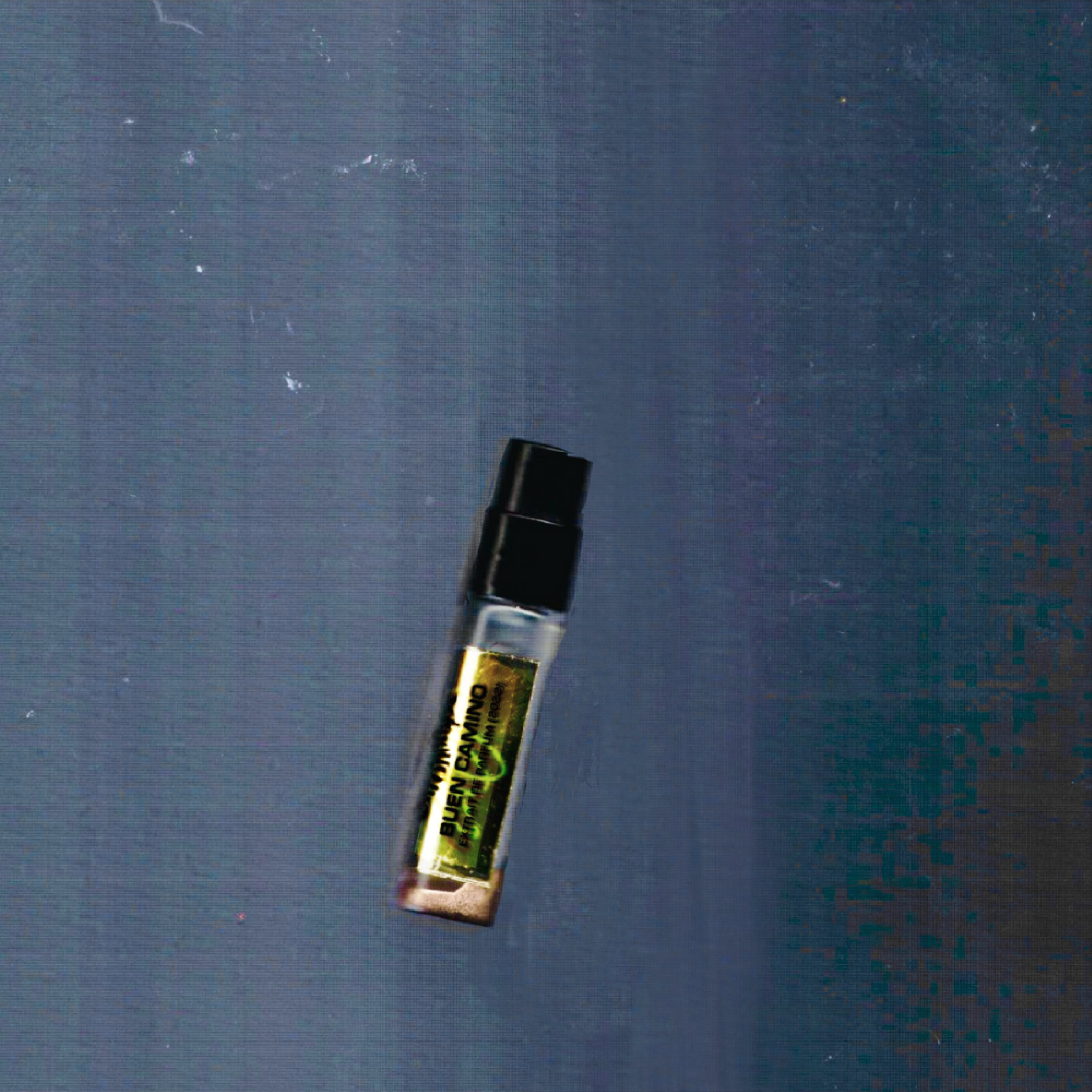 2mL spray sample of Chronotope Perfume’s Buen Camino Extrait de Parfum, featuring a golden enameled tip and matching Amberlit Gold label, shown against a dark gray background.
