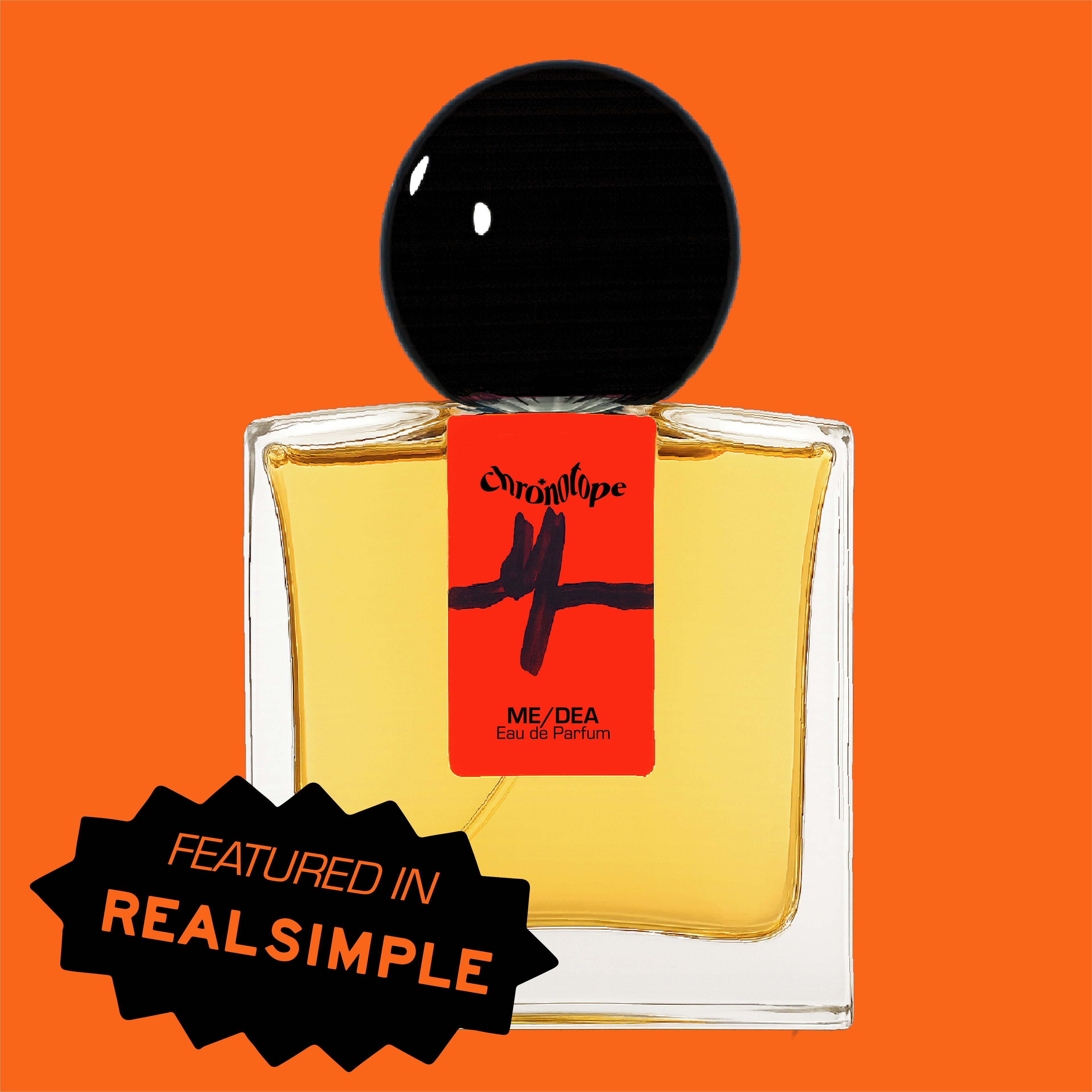 Digital rendering of Chronotope Perfume’s Me/dea Eau de Parfum 30 mL bottle from the brand’s Neon Series. The bottle features a fluorescent orange — or Safety Orange — label hand-marked by the perfumer with a black heart-monitor symbol depicting the final heartbeat before flatline, the last pulse forming the letter M for Me/dea. It contains amber perfume and is set against a matching Safety Orange background with a badge noting press coverage in Real Simple Magazine.