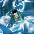A full, 30mL bottle of Intra Venus Eau de Parfum by Chronotopeis nestled into a nest of colored, silky, shining fabric that matches the color of the thumbprint on the bottle’s label.