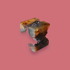 Fragmented resin cube split mid-air, with geologic striations and molten interior veins, suspended against a red background. Suggests disappearance, memory, and physical trace.