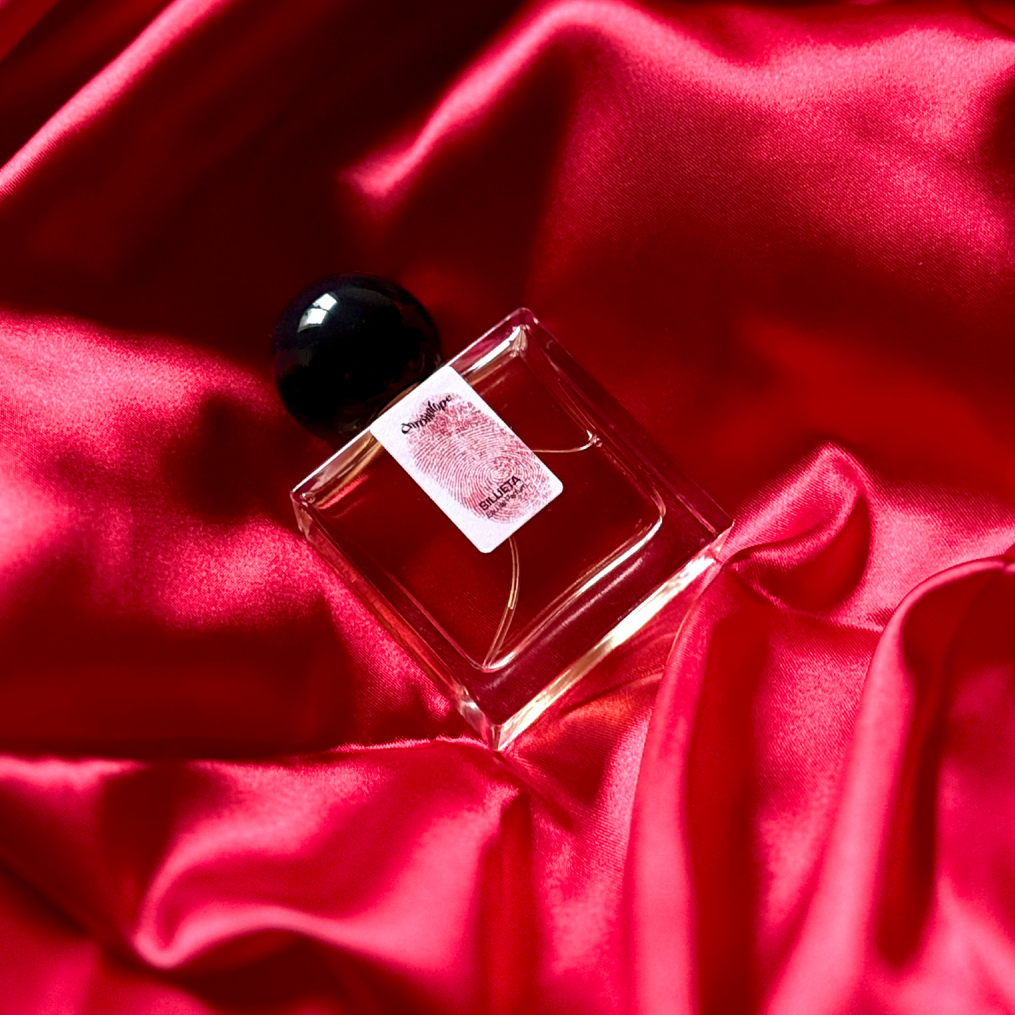Chronotope perfume’s Silueta EdP lies in a shimmering nest of fabric in the same blood red color as the thumbprint on the perfume bottle’s label.