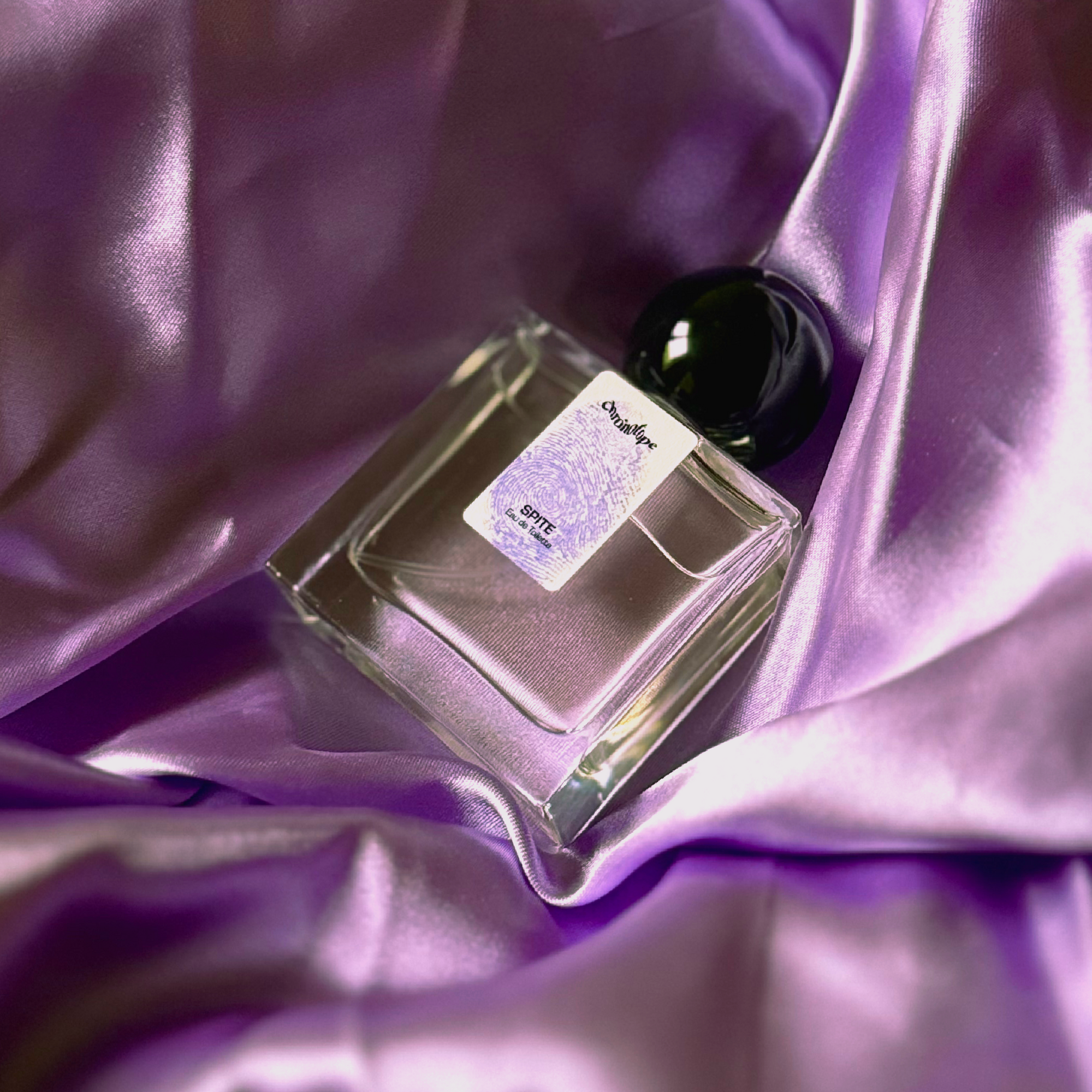 Chronotope perfume’s Spite EdT lies in a shimmering nest of fabric in the same mauve color as the thumbprint on the perfume bottle’s label.